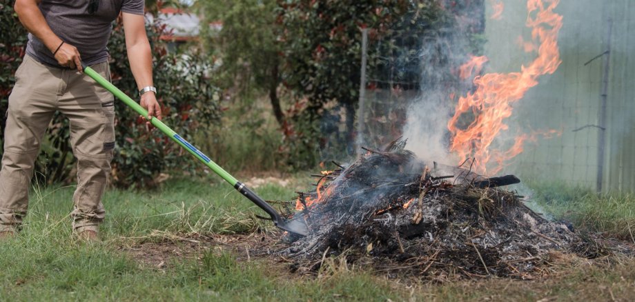 Man tending to fire controlled burn off of garden waste Man tending to fire controlled burn off of garden waste