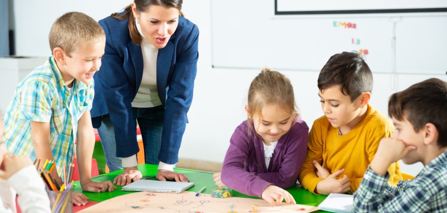 Teacher and pupils play a table game in elementary school class