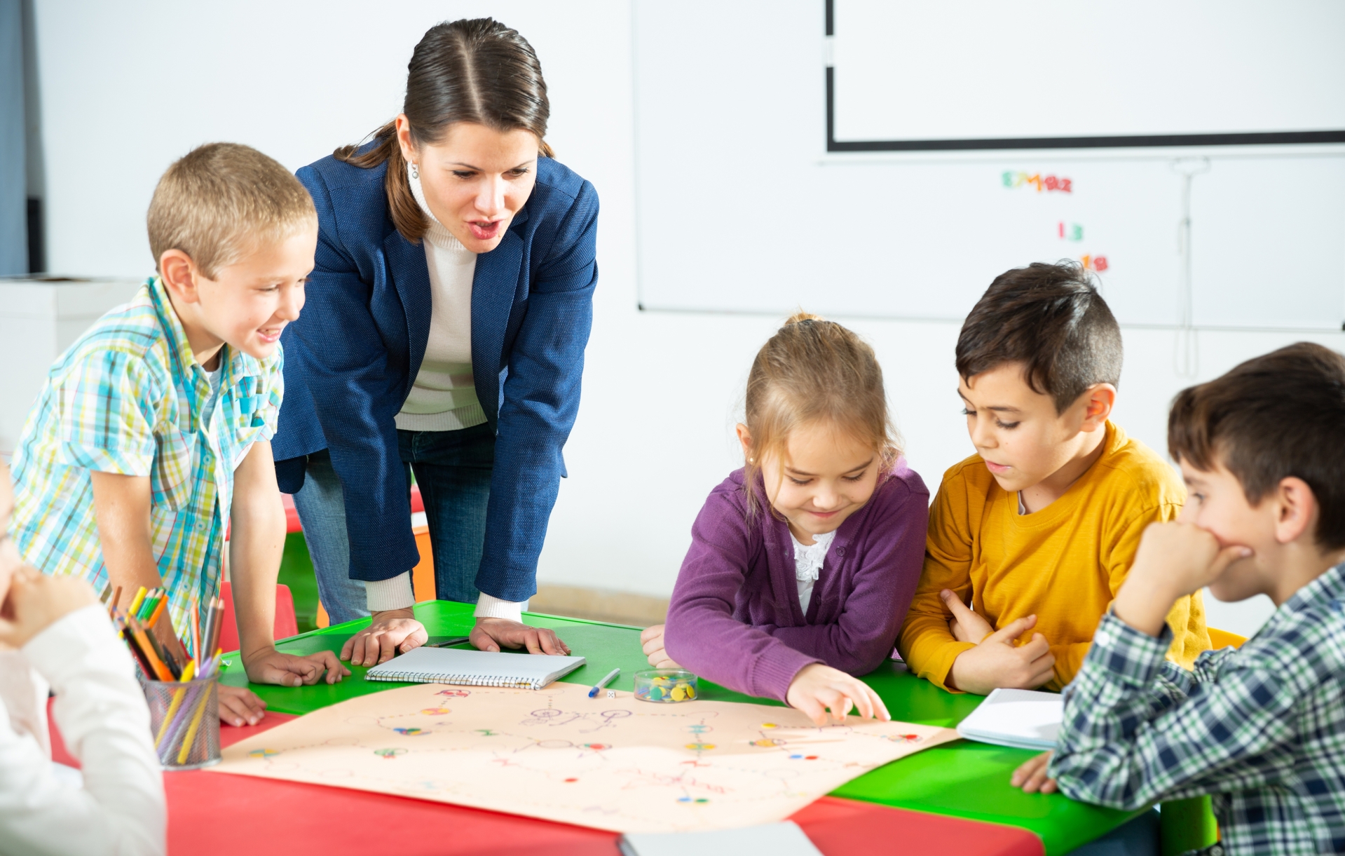 Teacher and pupils play a table game in elementary school class