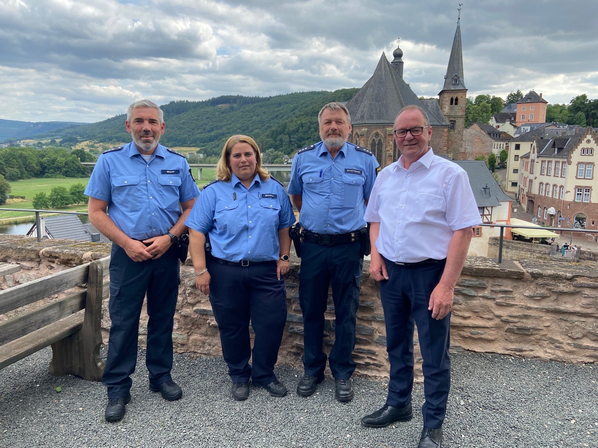Portrait der Bezirksbeamten der Polizeiinspektion Saarburg und Bürgermeister Jürgen Dixius mit Blick auf Saar und Altstadt - Polizeihauptkommissar Bernhard Schiffmann, Polizeioberkommissarin Silke Brausch, Polizeihauptkommissar Volker Braun