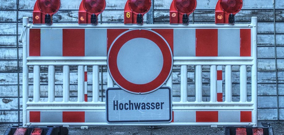 Nahaufnahme einer Straßensperre  mit Hochwasserwarnschild