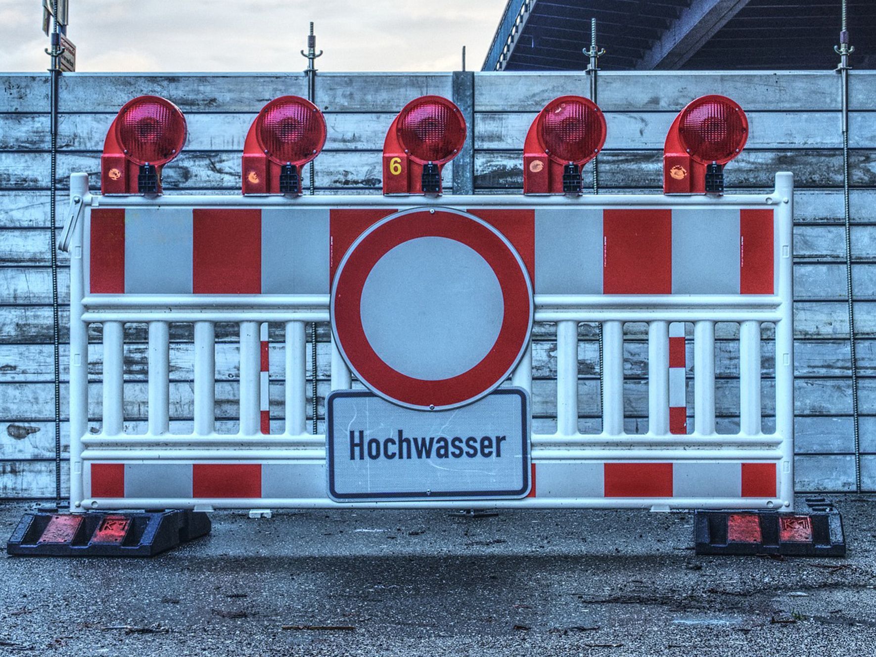 Nahaufnahme einer Straßensperre  mit Hochwasserwarnschild