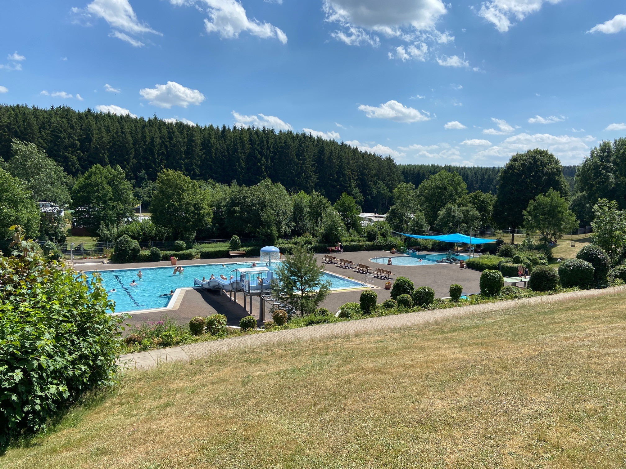 Blick auf die Becken des belebten Freibades in Kell am See im Sommer