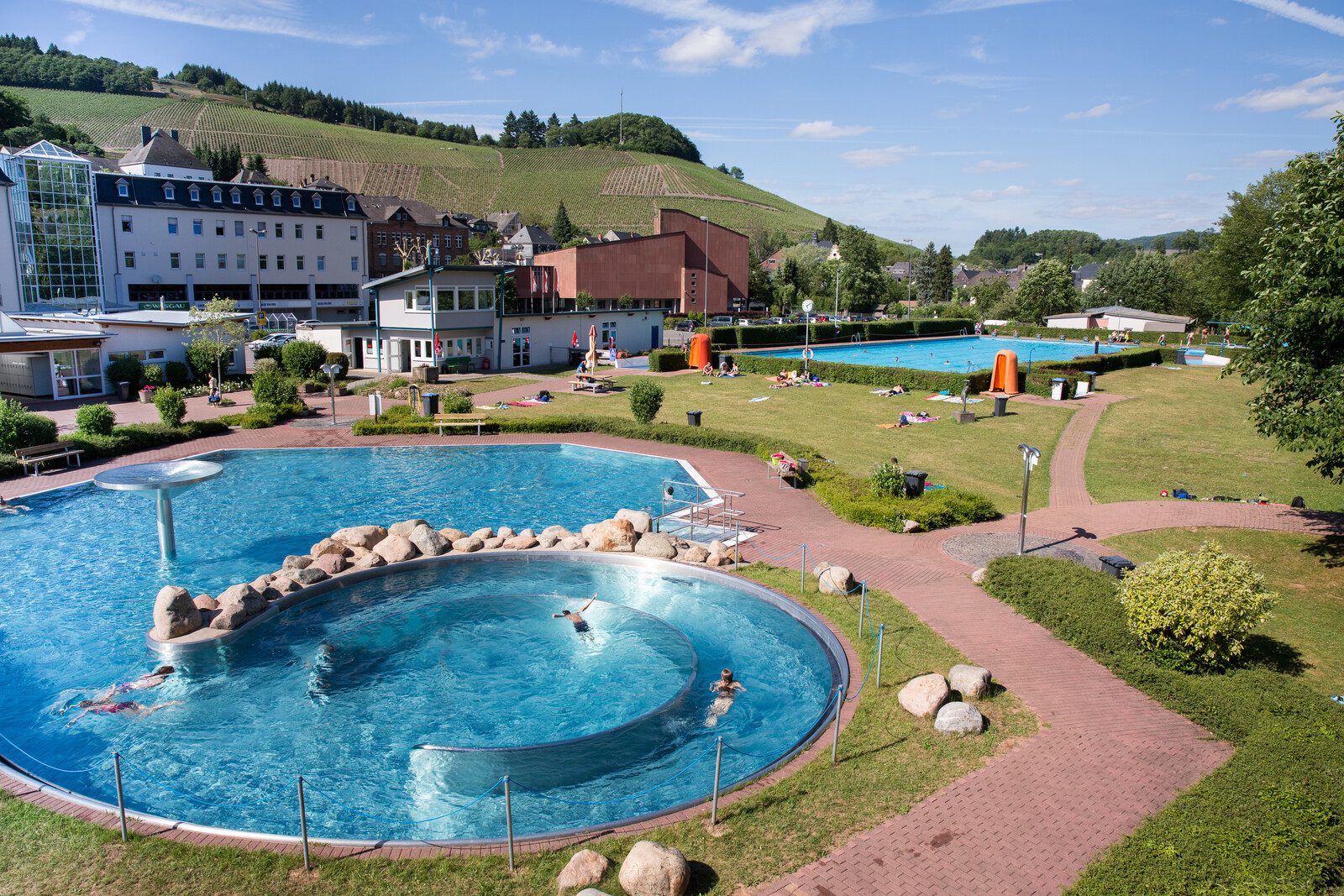 Blick von oben auf belebtes Nichtschwimmer- und Schwimmerbecken des Freibades in Saarburg